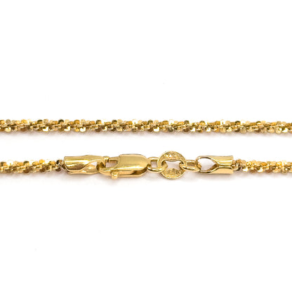 Close view of the lobster clasp and its stamped oval tag between two parallel runs of the textured yellow gold chain on white.