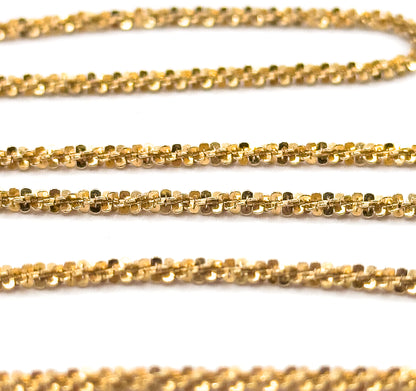 Extreme close-up filling the frame with several rows of the chain, revealing each tiny faceted popcorn link nestled against the next along the twisted yellow gold rope.
