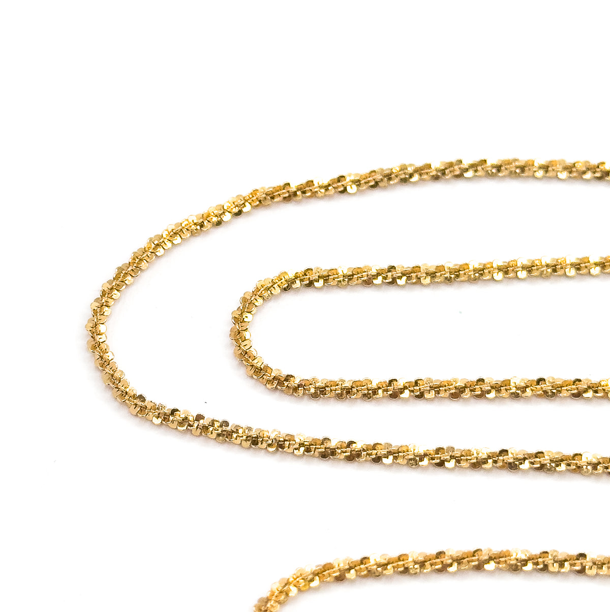 The chain coiled in long looping rows across a white background, each curve catching light so the faceted popcorn links sparkle along their full 18-inch run.
