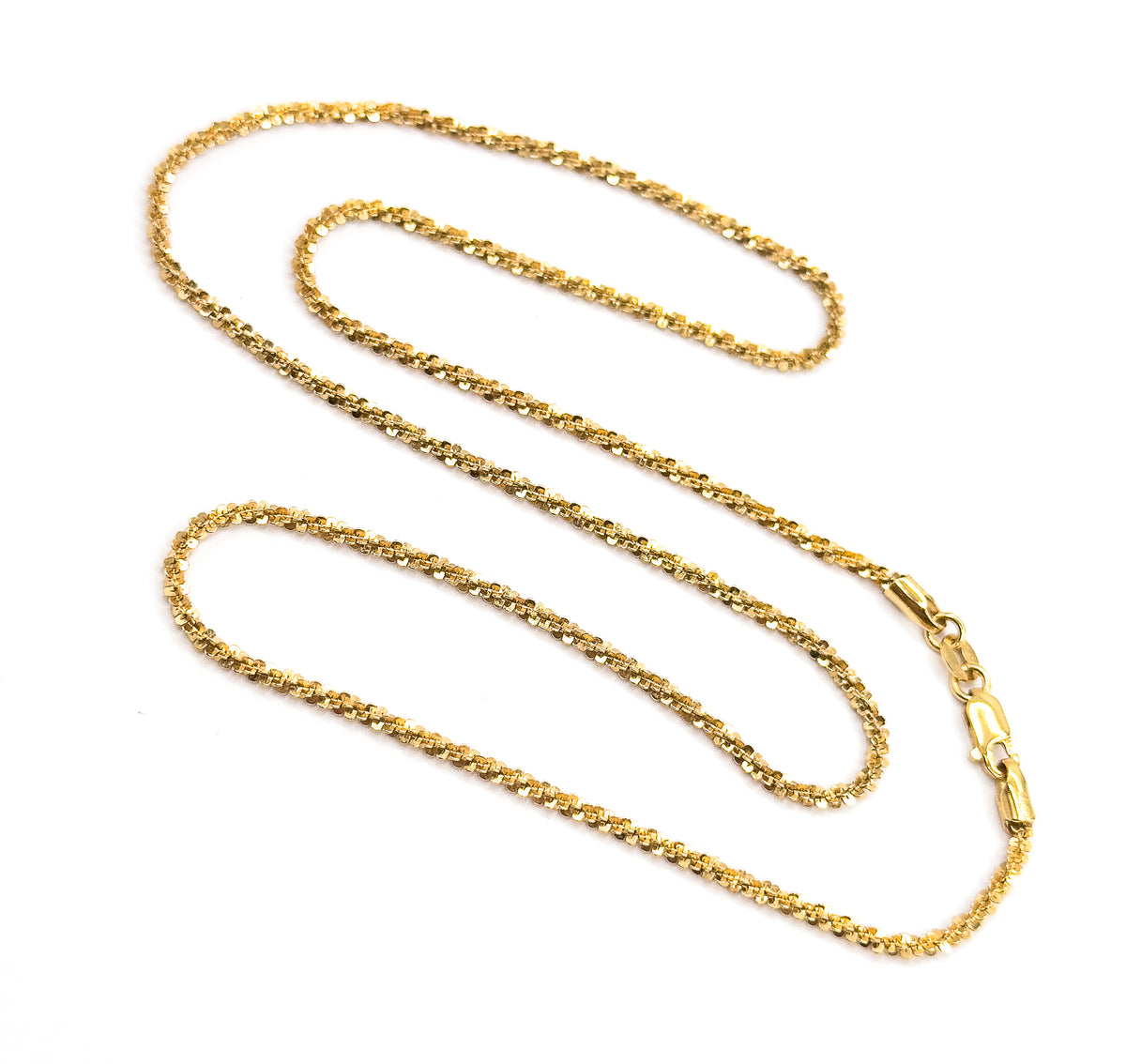 The whole necklace laid out in wide switchback loops with the lobster clasp and its ring open at lower right, showing how the faceted popcorn chain sparkles end to end.