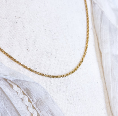 Margarita popcorn link necklace in 14K yellow gold, laid in a gentle curve across cream textured fabric with white lace-trimmed cloth at the edges.