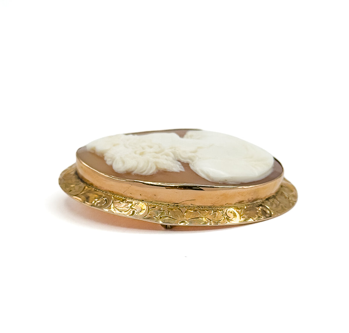A very low edge-on view against white, the eye almost level with the mounting so the plain gold bezel rim and the engraved floral gallery band beneath it read as two stacked ovals.