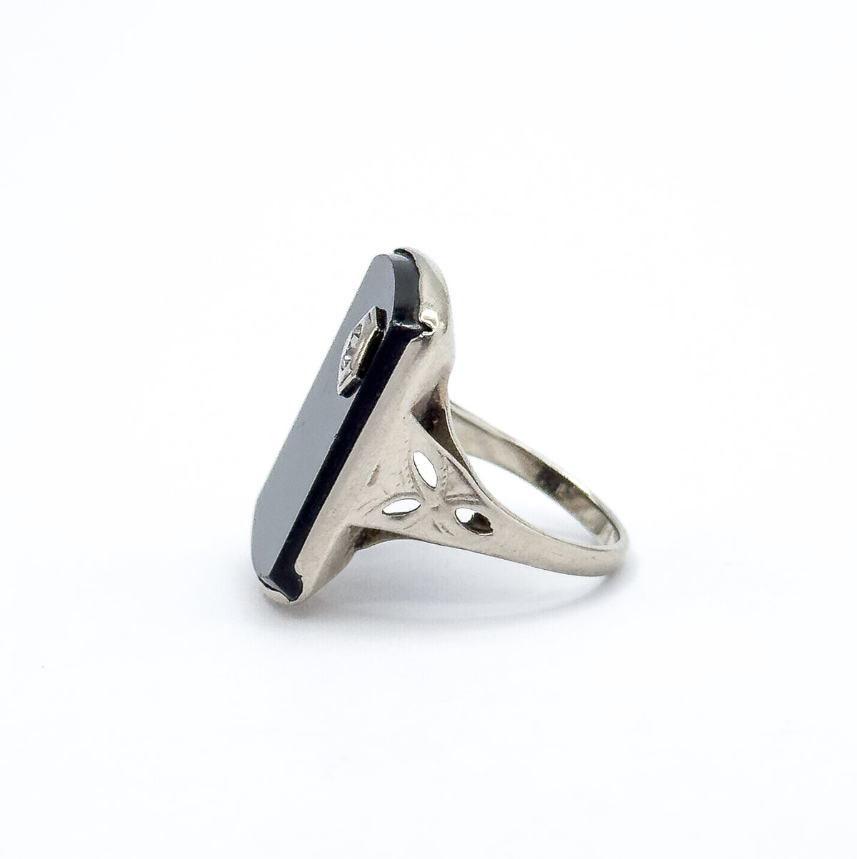 Almost the same view with slightly different angle, turned to a near-profile so the thin flat slab of onyx and its bezel prongs stand upright above the pierced shoulders and slender shank.