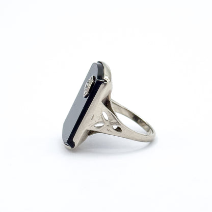 Almost the same view with slightly different angle, turned to a near-profile so the thin flat slab of onyx and its bezel prongs stand upright above the pierced shoulders and slender shank.