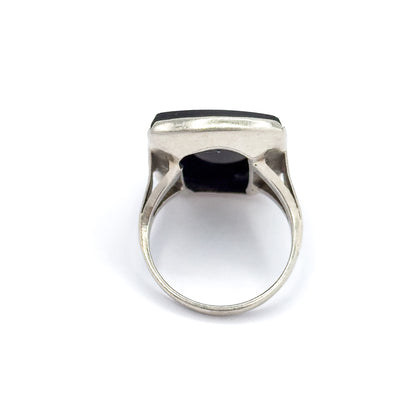 Viewed from behind against white, the open gallery frames the back of the black onyx, with the white gold bezel rim above and the shoulders' cutouts flanking the round shank.
