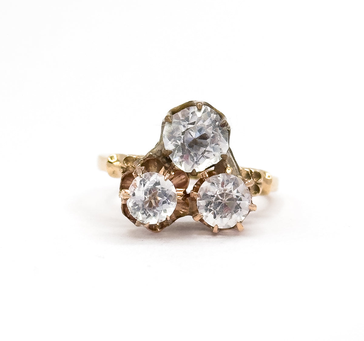Face-on view with the three colourless paste stones upright in their prong baskets — one larger above two rounds — and the orange blossom shoulders flaring out either side of the yellow gold shank.