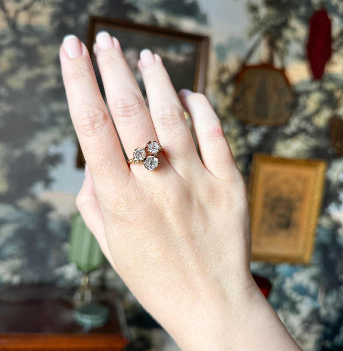 The full hand is shown back-on at a distance, the ring small on the third finger, giving a sense of its scale against the knuckle and fingers.