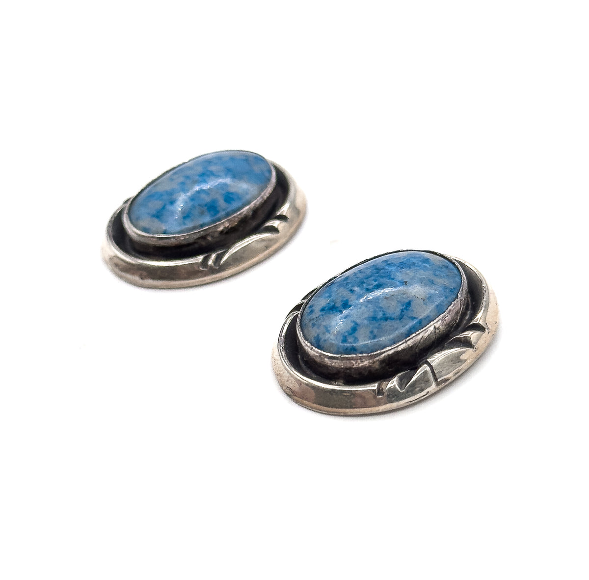 Both earrings angled on a white background, showing the oval bezels, dark recessed borders and leaf-like patterning in the sterling silver surrounds.