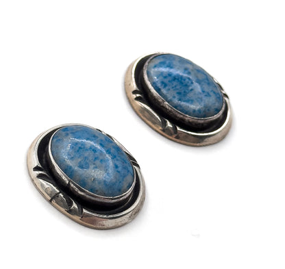 Both earrings set diagonally and seen from a lower angle, so the thickness of the oval sterling silver backs and the stamped detailing running down each side come into view.