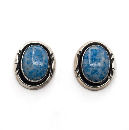 The pair side by side face up on a plain white background, straight on, showing both oval cabochons and the darkened silver surrounds with their leaf-shaped side detail matching each other.