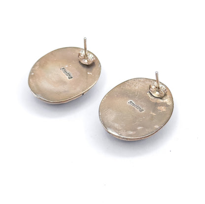 Reverse view of both earrings on white, showing the plain oval backs each stamped "sterling", with straight post and butterfly back fitted behind.