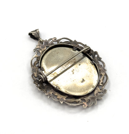 The reverse, showing the plain oval back plate stamped 800, the hinged pin stem and catch across it, and the openwork acanthus border with the bail at top.
