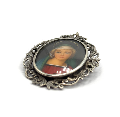 Tilted at an angle on white, the raised bezel rim around the glass and the depth of the openwork acanthus border catch the light, the painted face turned slightly away.