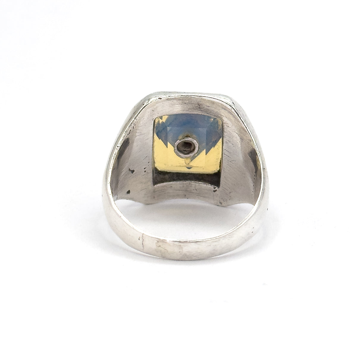 Back of the ring head seen straight on, the open bezel revealing the underside of the opaline glass and the small round seat holding the paste, with the shank curving below.