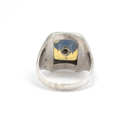 Back of the ring head seen straight on, the open bezel revealing the underside of the opaline glass and the small round seat holding the paste, with the shank curving below.