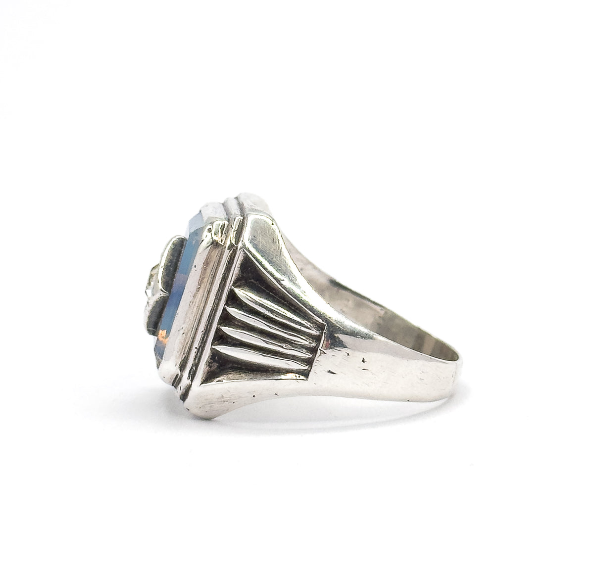 Profile from the opposite side, the fanned ribs of the shoulder sweeping up to the stepped bezel, with the edge of the opaline glass and the tapering shank in view.