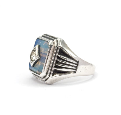 Angled three-quarter view from the front, the rectangular opaline glass glowing pale blue in its stepped bezel with the prong-set colourless paste at its side.