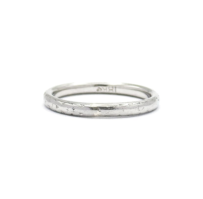 The ring stands upright on a white background, showing the full circle of the narrow domed shank with faint engraved marks along the outside and a stamp inside.