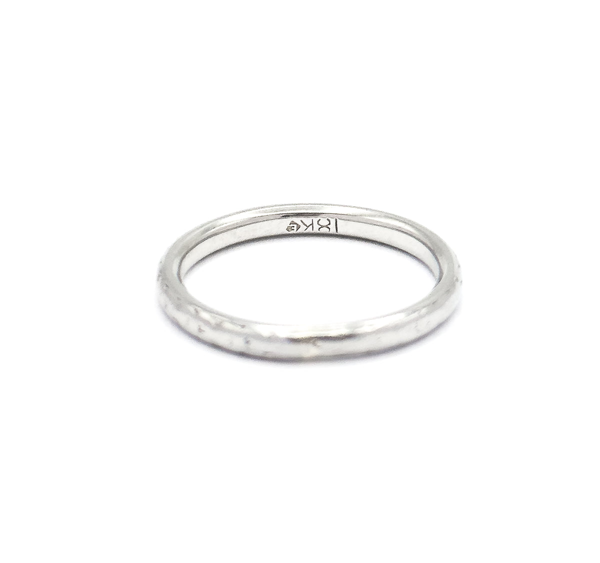Tilted forward on a white background, the band shows its inner surface with a small stamp inside the shank and the rounded outer edge curving toward the viewer.
