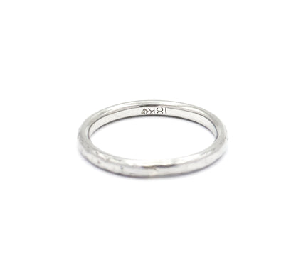 Tilted forward on a white background, the band shows its inner surface with a small stamp inside the shank and the rounded outer edge curving toward the viewer.