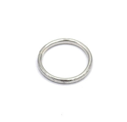 Viewed from above at a slight tilt, the band lies flat so the circular opening reads as a full round hole, the slim domed shank forming an even ring with soft light along its upper curve.