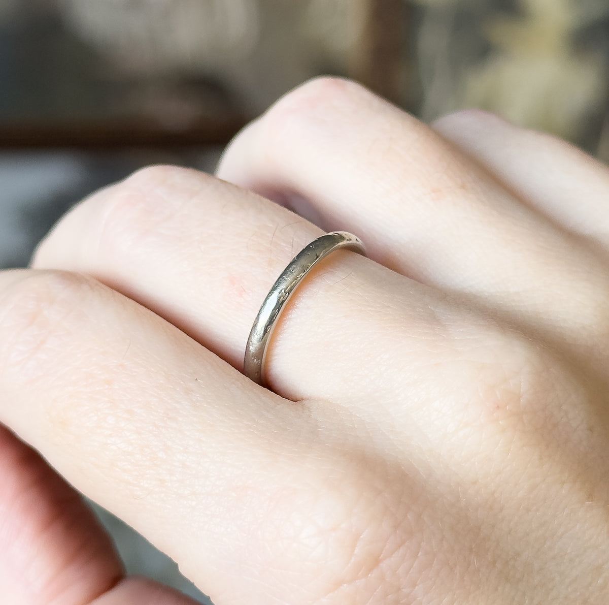 A mid-century engraved band ring in 14K white gold, shown on a finger with the slightly domed shank catching light across its smooth surface.