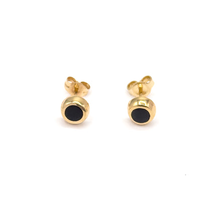 The pair is seen from slightly above, so each black enamel face tilts into view while the yellow gold butterfly backs sit high behind, showing the full front-to-back depth.