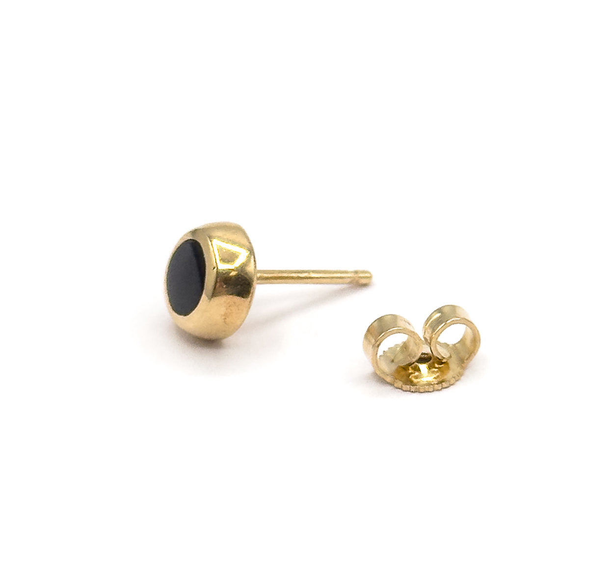 A black enamel stud earring in 14K yellow gold, shown side-on against white with its round bezel, straight post and separate butterfly back beside it.