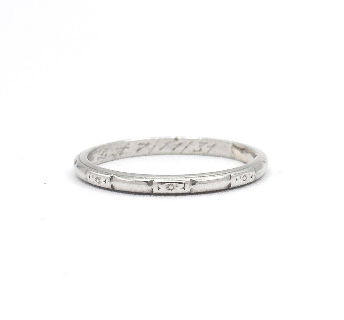 The band stands upright on a white background, its full circle visible, with star and geometric etching across the outer shank and script engraving inside the back.