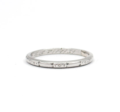The band stands upright on a white background, its full circle visible, with star and geometric etching across the outer shank and script engraving inside the back.