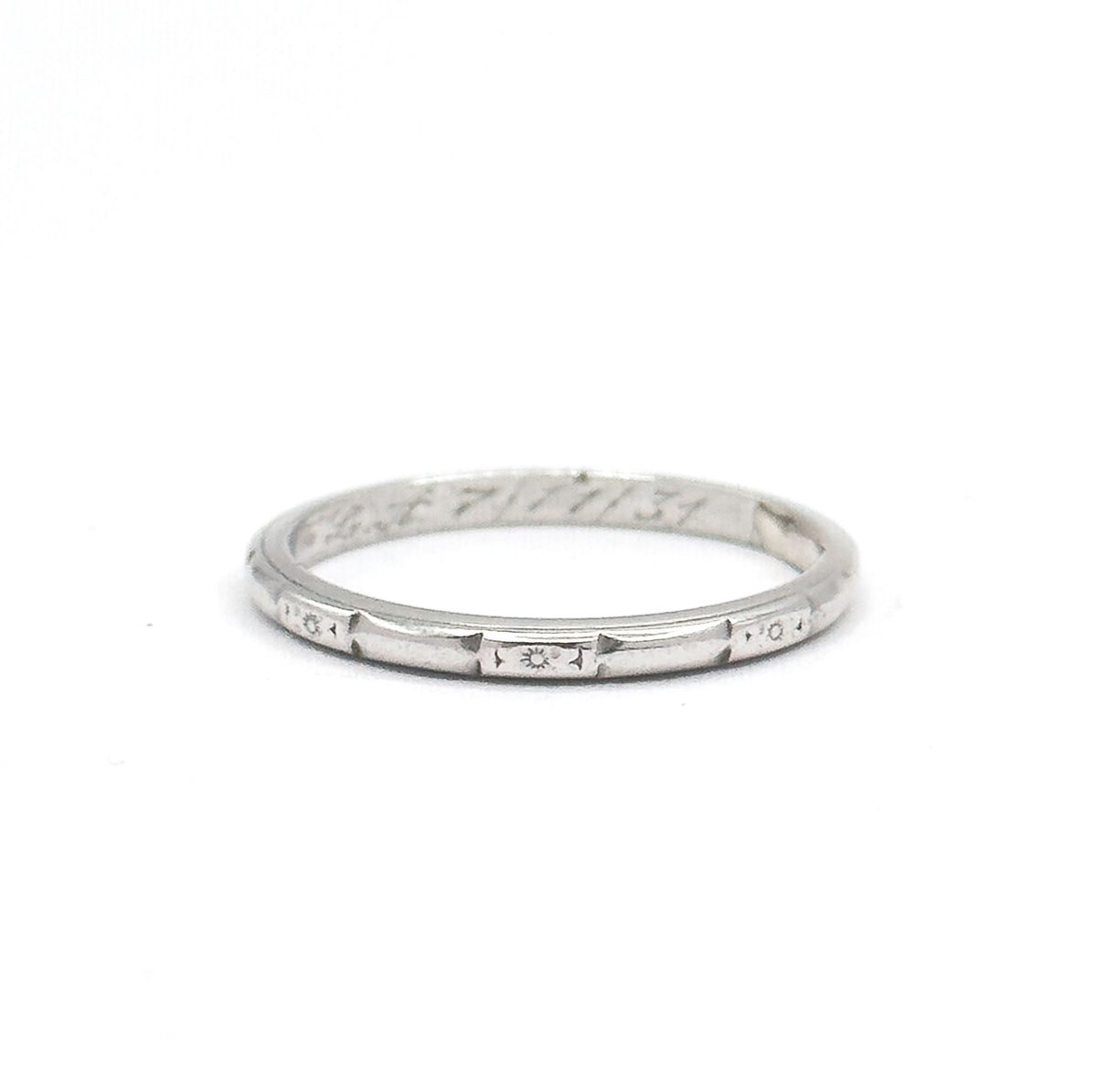 Seen almost level from the front, the slim hoop reads as a narrow ellipse with three star-centred etched panels spaced along the front of the shank and the inscription curving across the far inner wall.
