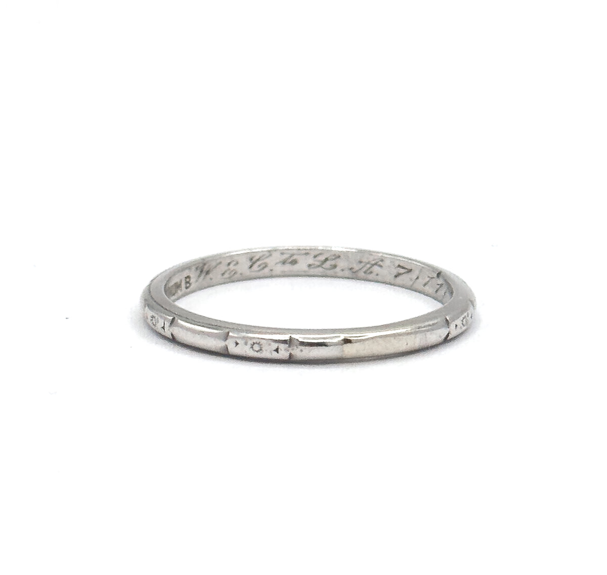 Standing upright against plain white, the band shows its full circle with the stamp and inscription across the inner far wall and a tiny sunburst motif centred in a panel on the near lower rim.