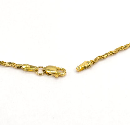 Close view of the open lobster clasp and its ring at one chain end, facing the small tapered end cap and stamped tag on the other, both on white.