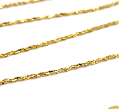 Four parallel runs of the crinkle chain stretched taut on the diagonal across white, the nearest one sharply in focus so each flat twisted link glints individually.