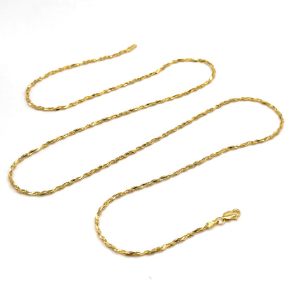 The whole chain laid out in three long serpentine loops on white, showing its full length at once with the lobster clasp and end tag resting at the lower right.