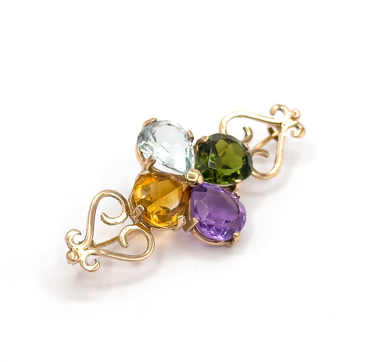 Angled three-quarter view on white, the four pear stones tilted toward the camera in their prongs while the rose gold scroll ends recede to either side.