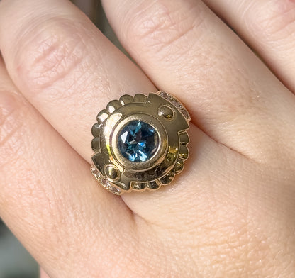 Close overhead view shown on a finger, the whole round face filling the knuckle so its width reads against the skin, white sapphires clustered at opposite edges of the bezel.