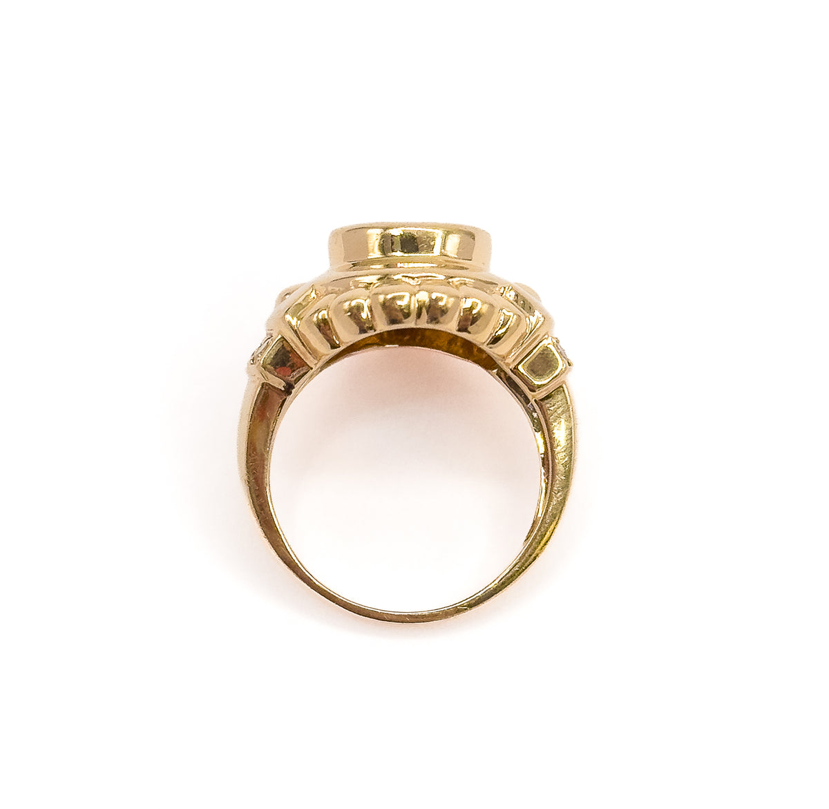 Viewed straight on from the end so the open circle of the shank frames empty space, with the tall bezel wall, scalloped gallery and rounded yellow gold band shown in profile.