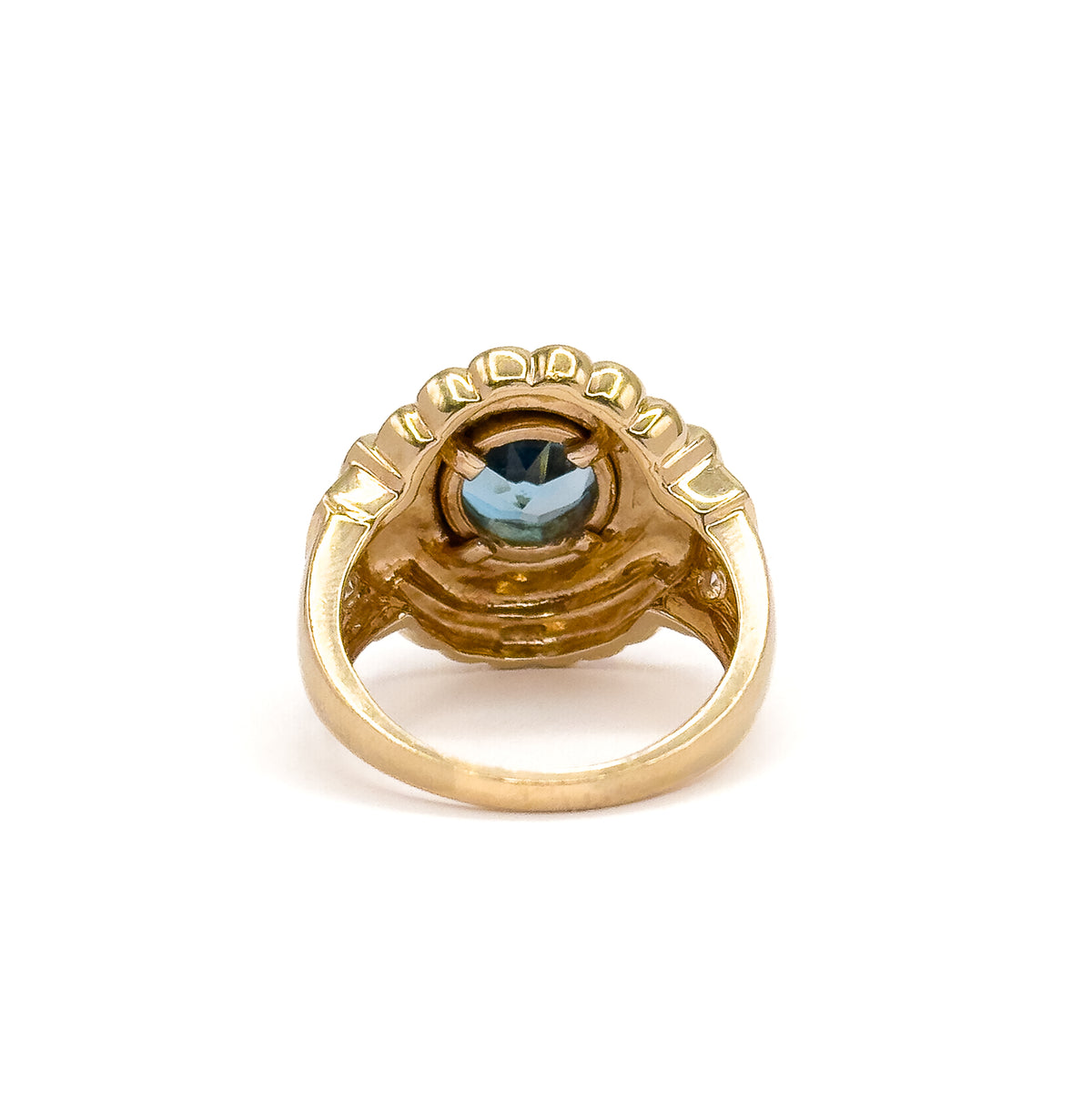 Seen from behind and below, the open shank curving up to the hollowed underside of the gallery, with the back of the blue topaz visible through the bezel opening.