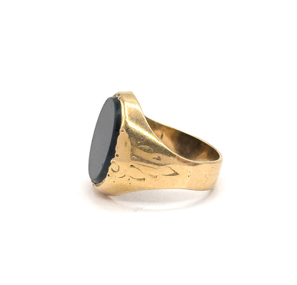 Turned so the bloodstone faces left in near profile, this view shows the full engraved shoulder sweeping right into the thick shank and the open circle of the band.