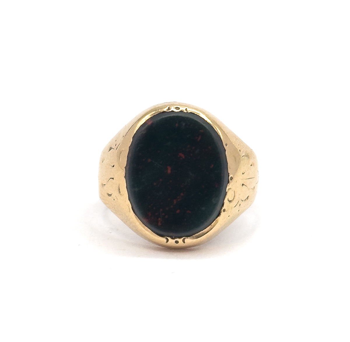 Close frontal view cropped tight on the bezel, the oval bloodstone's red speckles scattered over dark green, with small punched marks visible at the top and bottom of the gold rim.