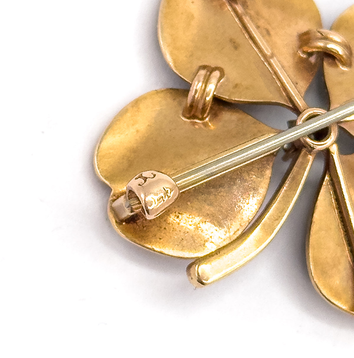 Close-up of the reverse showing the long pin stem crossing the smooth 14K yellow gold leaves, with the folding bale and a small stamped maker's mark near one leaf tip.