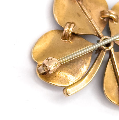 Close-up of the reverse showing the long pin stem crossing the smooth 14K yellow gold leaves, with the folding bale and a small stamped maker's mark near one leaf tip.