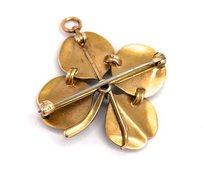 Reverse from a lower angle, the pin stem lying diagonally into its C-catch, with the small gold loops that anchor each seed pearl ringing the plain leaf backs and the bale ring at the top.