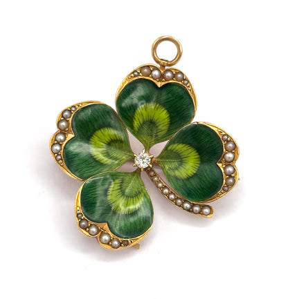 Close front view filling the frame, the four green enamelled leaves shaded pale at their hearts, seed pearls following every scalloped edge and the folding bale ring standing at the top.