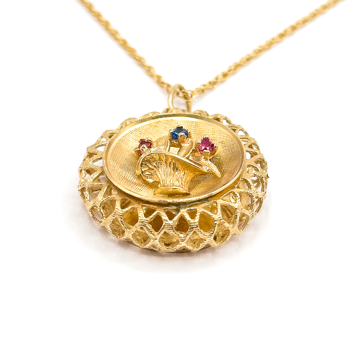 Tipped forward so the deep domed lattice underside swells toward the viewer beneath the oval face, the fine chain rising in a long diagonal to the upper right from the small bail ring.