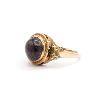 Side profile against white with the ring upright, the bezel-set brown cabochon rising high on its openwork gallery above the decorated shoulders and tapering shank.