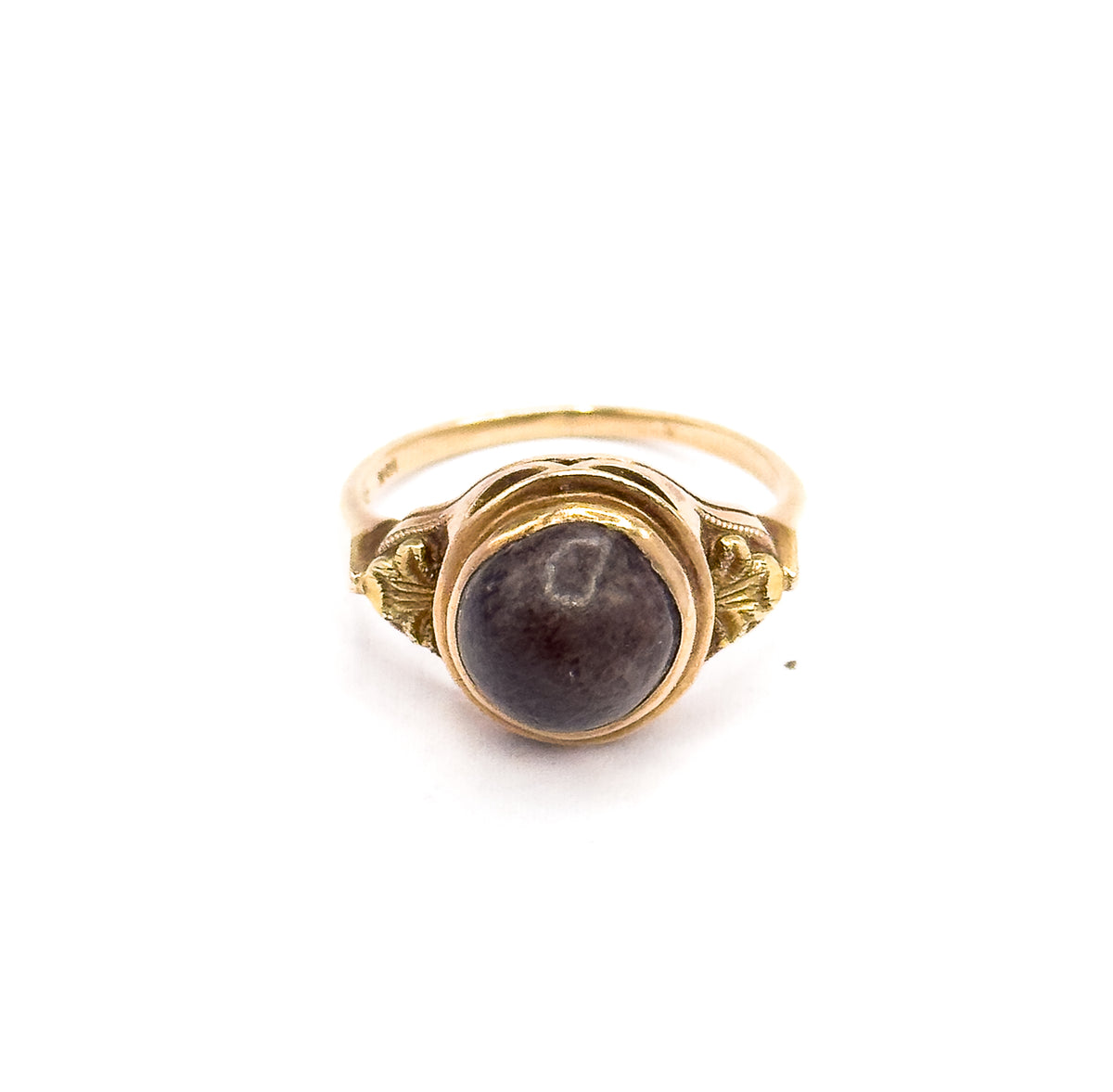 Upright against a plain white background with no hand, the face square to the camera so the round brown cabochon, its rose gold bezel and the leafy shoulders sit above the thin shank.