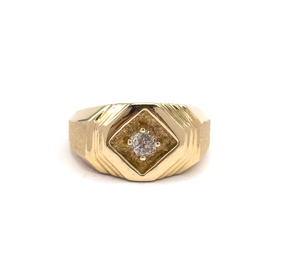Viewed head-on and upright against white, the diamond-shaped recessed face sits square to the camera with its prong-set round diamond centred and grooved shoulders flaring symmetrically either side.