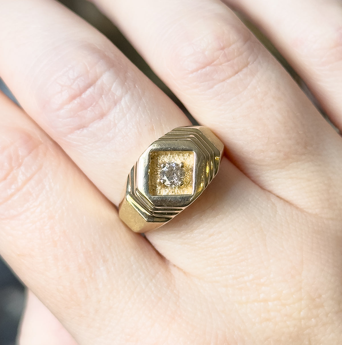 Shown on the finger from above with the hand relaxed, the diamond-shaped recess set square to the camera and the grooved shoulders sloping away between the neighbouring fingers.
